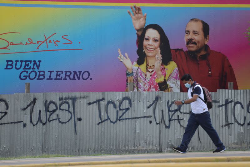 Man walks by billboard showing Nicaragua's President Ortega and Vice President Murillo in Managua