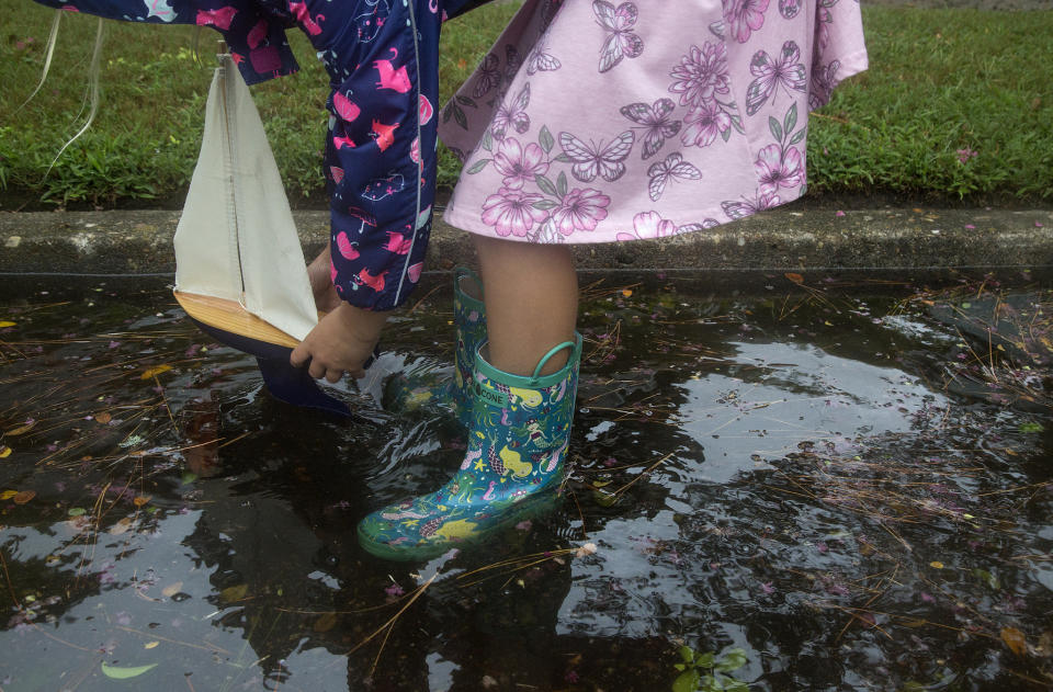 Lyla Shaw, 7, plays with a toy sailboat in floodwaters in Larchmont after Hurricane Dorian brought heavy wind and rain to Norfolk, Va., on Friday, Sept. 6, 2019. (Kaitlin McKeown/The Virginian-Pilot via AP)