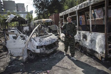 A pro-Russian rebel walks past burnt-out vehicles in an area that was recently shelled in Donetsk, eastern Ukraine, September 16, 2014. REUTERS/Marko Djurica