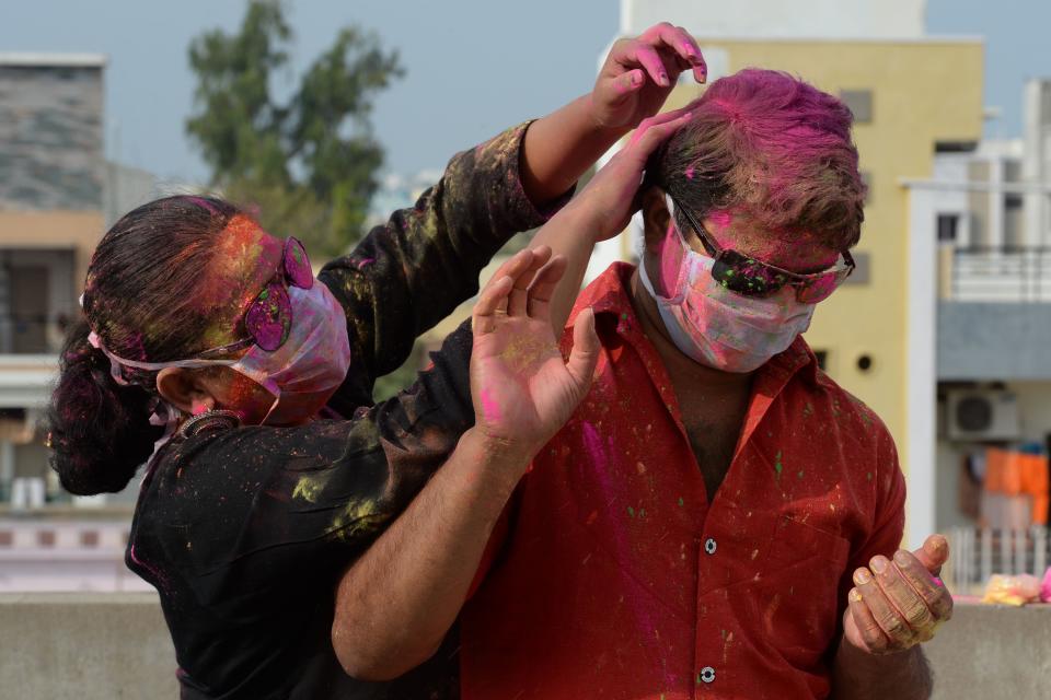 A couple wearing facemasks as a preventive measure against the COVID-19 coronavirus, apply smear their faces with coloured powder during a friends gathering the celebrate 'Holi', the Hindu spring festival of colours, in Hyderabad on March 8, 2020. - Holi, the popular Hindu spring festival of colours is observed in India and across countries at the end of the winter season on the last full moon of the lunar month. (Photo by NOAH SEELAM / AFP) (Photo by NOAH SEELAM/AFP via Getty Images)