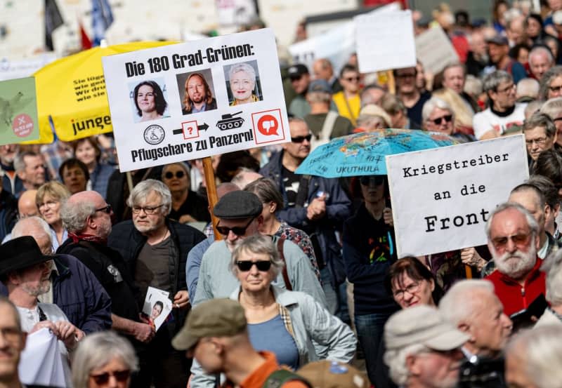 People take part in the traditional Easter march under the motto "Warlike - Never Again" with signs reading "The 180 Degree Greens, Plowshares to Tanks", "Warmongers to the Front". Fabian Sommer/dpa