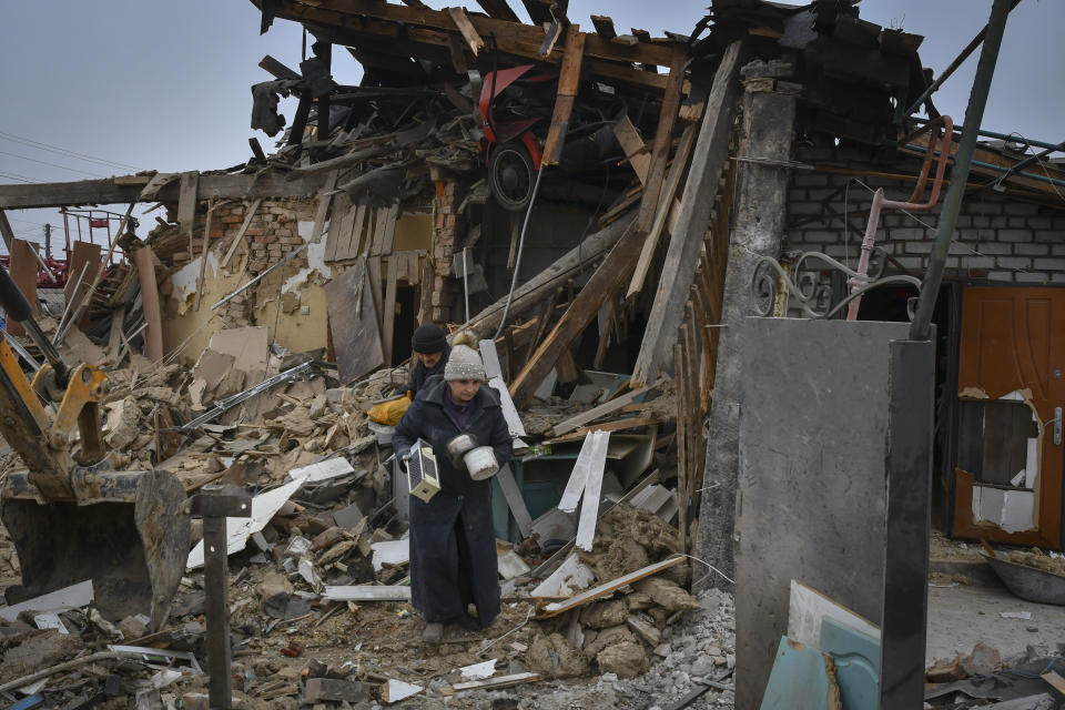 Local residents carry their belongings as they leave their home ruined in the Saturday Russian rocket attack in Zaporizhzhya, Ukraine, Sunday, Jan. 1, 2023. (AP Photo/Andriy Andriyenko)