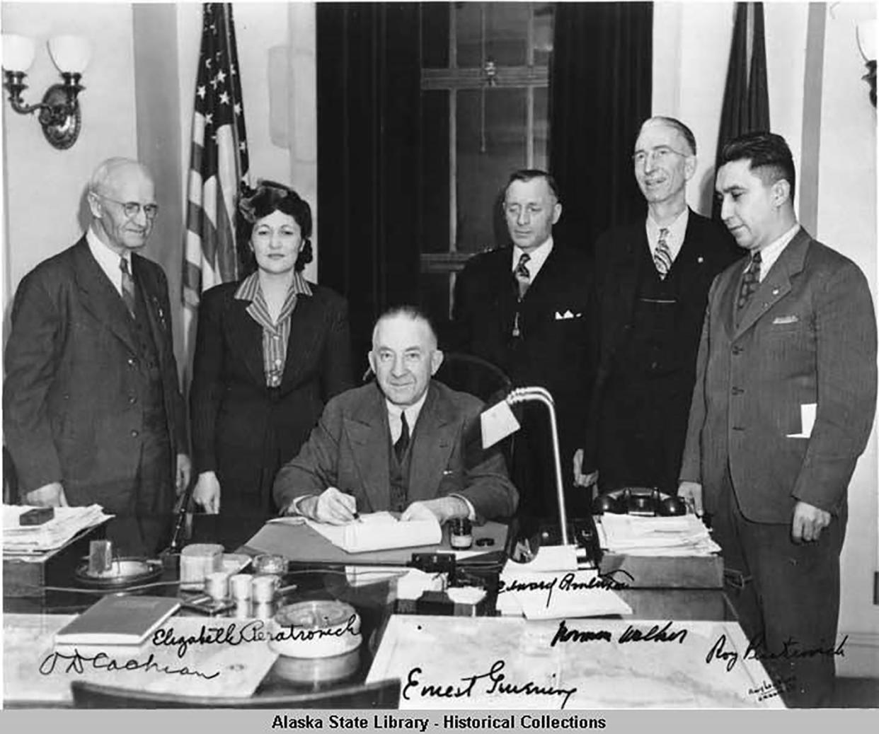 Governor Gruening (seated) signs the anti-discrimination act of 1945. Alaska Territorial Governors. Witnesses are (left to right) O. D. Cochran, Elizabeth Peratrovich, Edward Anderson, Norman Walker, and Roy Peratrovich. Image: Amy Lou Blood - Ordway's. (Photo: Alaska State Library - Historical Collections)