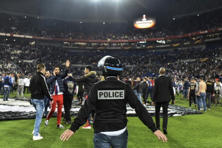 Police stand on the pitch after Besiktas' and Lyon's supporters fought before the UEFA Europa League first leg quarter final football match April 13, 2017, at the Parc Olympique Lyonnais stadium in Decines-Charpieu