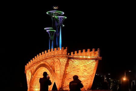 People take pictures in front of a "Golden Bridge on Silk Road" installation, set up ahead of the Belt and Road Forum, outside the National Convention Centre in Beijing, China May 11, 2017. Picture taken May 11, 2017. REUTERS/Stringer