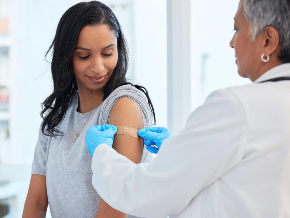 Healthcare, woman and doctor with plaster, vaccination and consultation in a hospital, cure and disease. Female patient, client and medical professional with band aid, care and injection for safety