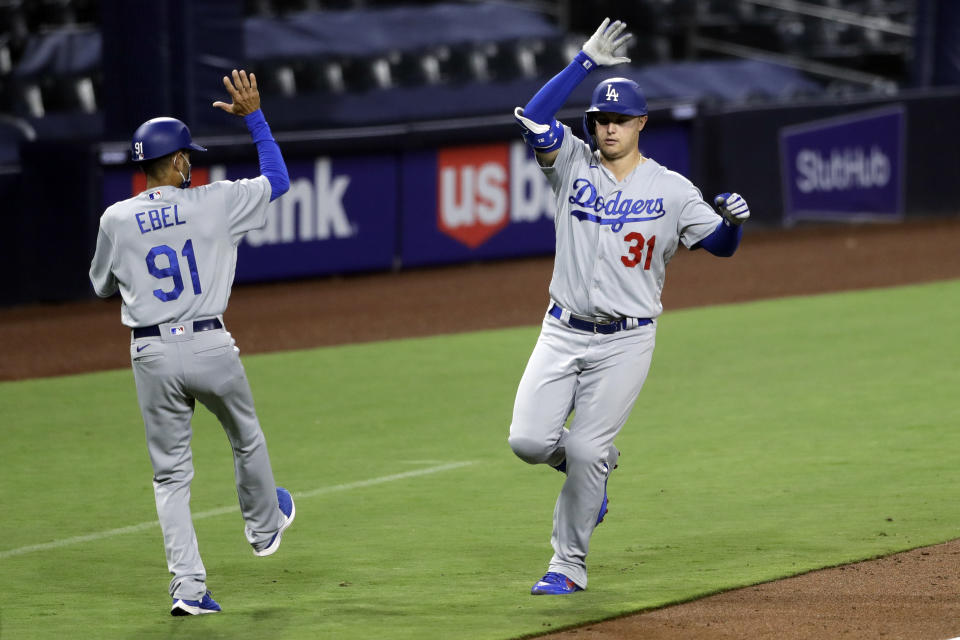 Los Angeles Dodgers' Joc Pederson, right, reacts with third base coach Dino Abel after hitting a three-run home run during the sixth inning of a baseball game against the San Diego Padres, Wednesday, Aug. 5, 2020, in San Diego. (AP Photo/Gregory Bull)