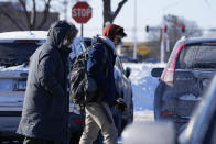 People are bundled up as they walk to a grocery store in Arlington Heights, Ill., Sunday, Jan. 14, 2024. A wind chill warning is in effect as dangerous cold conditions continue in the Chicago area. (AP Photo/Nam Y. Huh)