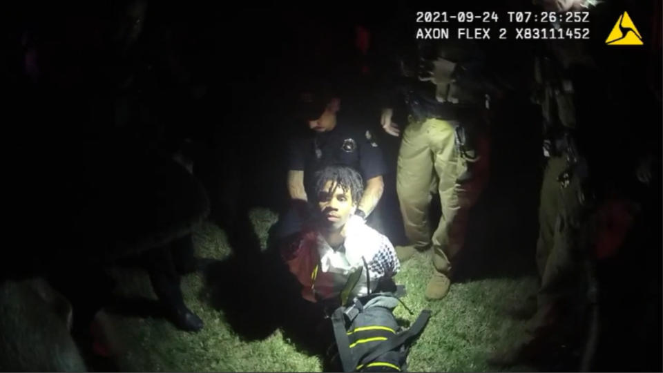 In this image from body camera video provided by Sedgwick County, police put Cedric “C.J.” Lofton, 17, into a body-length restraining device called a WRAP outside his home in Wichita, Kan., on Sept. 24, 2021. His foster father, unable to deal with a teen who seemed to be in the throes of schizophrenia, had called Wichita police. When they arrived, Cedric refused to leave the porch and go with them; he was obstinate but afraid, meek but frantic. (Sedgwick County via AP)