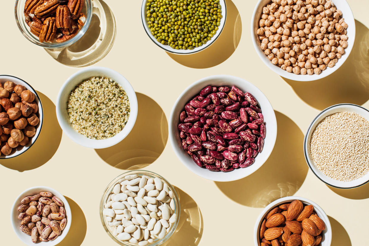 Various kinds of vegan protein sources on beige background. Set of food supplements. Gluten free cereals as ground hemp seeds, quinoa. Nuts and legumes (green mung beans, chick-pea, red lentil, kidney bean, almonds, hazelnuts). Flat lay, top view