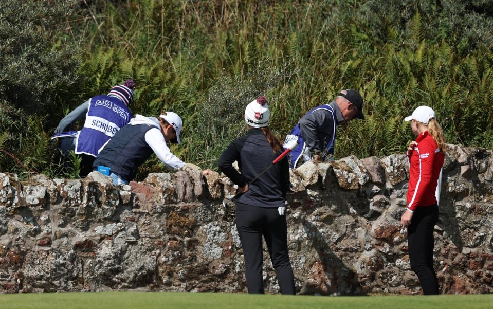 Catriona Matthew of Scotland and Caddies climb over a wall on the 2nd green whilst Louise Duncan of Scotland looks on during Day Two of the AIG Women's Open at Muirfield on August 05, 2022 in Gullane, Scotland - GETTY IMAGES