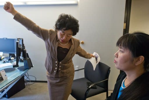 Former China labor camp detainee, Wang Chunying (L), demonstrates a position she was forced to take while handcuffed between two beds as her compatriot Ma Chunmei looks on during an interview at the AFP offices in Washington, DC, on April 30, 2013