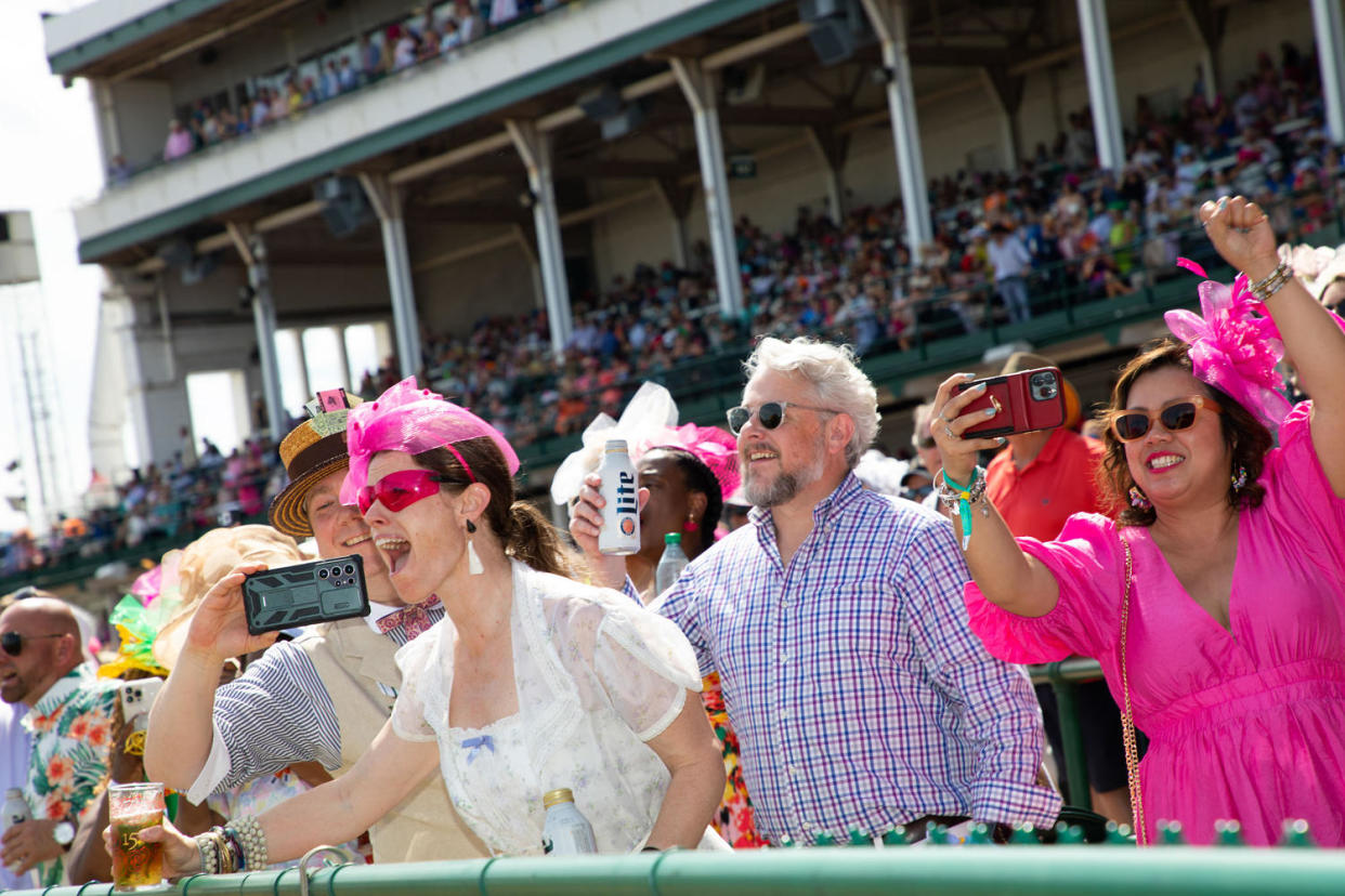 Fans cheer and take photos in the grandstand at Churchill Downs.