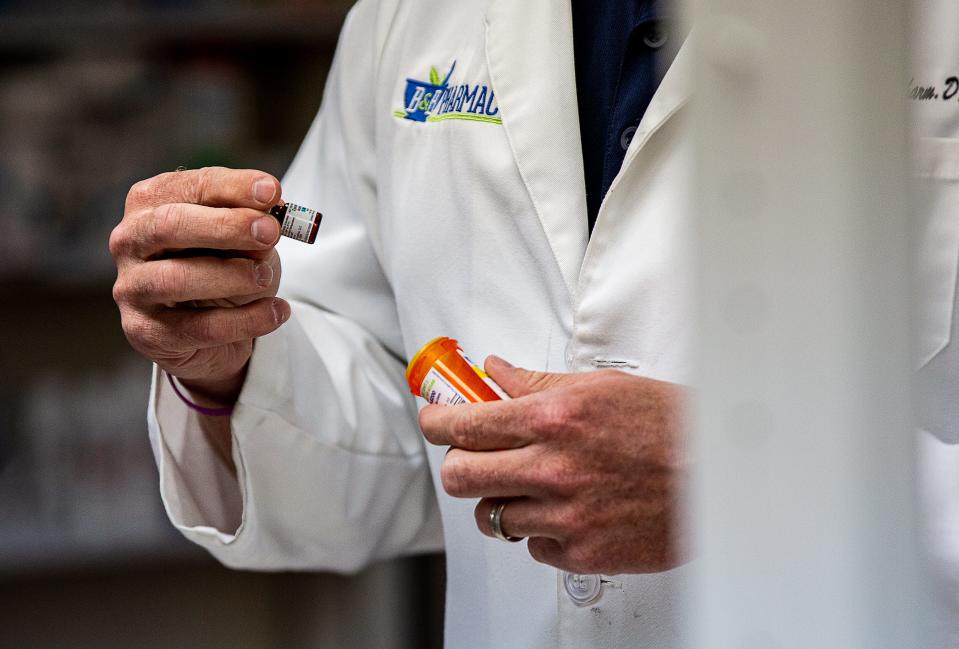 Pharmacist Ashley Buckman fill a prescription during a busy afternoon at B & B Pharmacy in Shepherdsville.