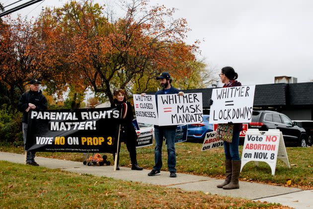From left to right, A man who wished not to be named, Lynn Mills, a pro-life advocate, Jeff Domsic, of Canton, and Cydney Domsic, of Canton, hold signs in addition to the ones they added to the lawn opposing Whitmer before she was set to arrive at a campaign event in Canton, Michigan, on Oct. 26. (Photo: Brittany Greeson for HuffPost)