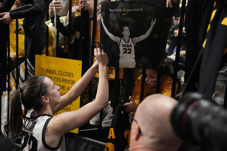 Iowa guard Caitlin Clark (22) signs autographs after the team's NCAA college basketball game against Michigan, Thursday, Feb. 15, 2024, in Iowa City, Iowa. Clark set a new NCAA women's career scoring record. (AP Photo/Matthew Putney)