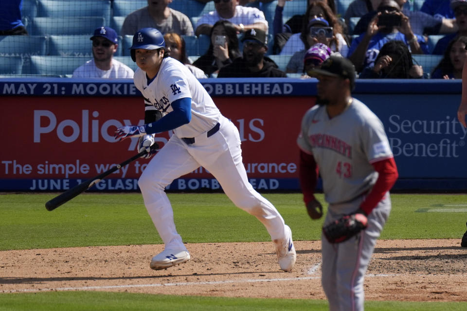 Los Angeles Dodgers' Shohei Ohtani, left, heads to first after hitting a walk-off single as Cincinnati Reds relief pitcher Alexis Diaz watches during the 10th inning of a baseball game Sunday, May 19, 2024, in Los Angeles. The Dodgers won 3-2. (AP Photo/Mark J. Terrill)