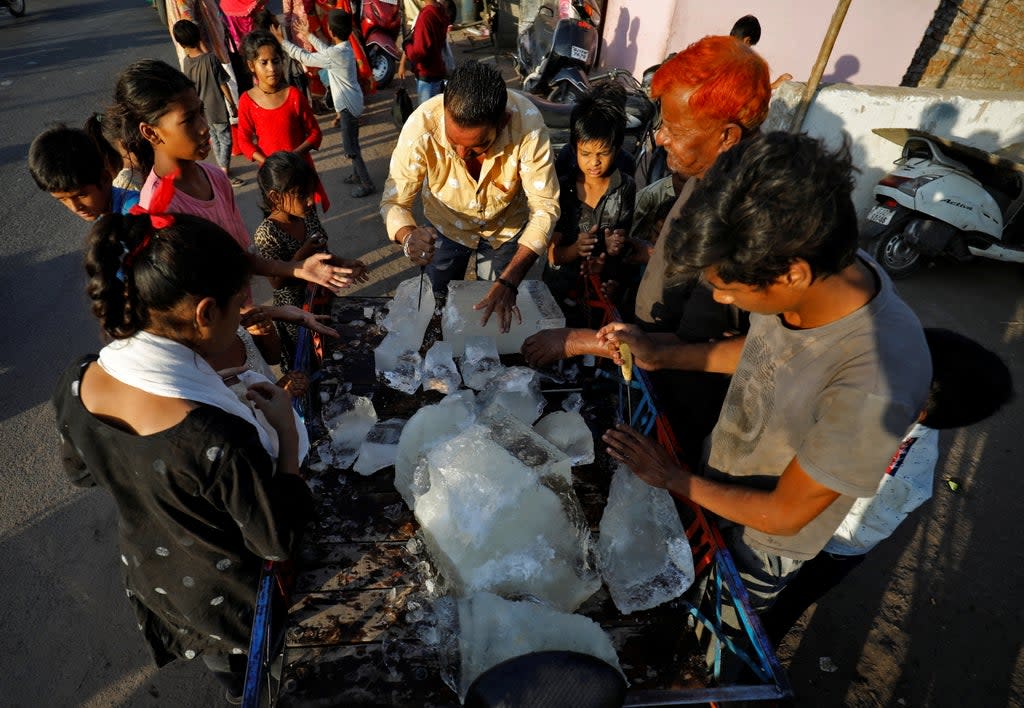 A man breaks a block of ice to distribute it among the residents of a slum during hot weather in Ahmedabad (REUTERS)