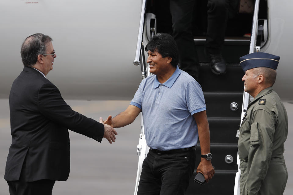 Mexican Foreign Minister Marcelo Ebrard, left, welcomes former Bolivian President Evo Morales in Mexico City, Tuesday, Nov. 12, 2019. Mexico granted asylum to Morales, who resigned on Nov. 10 under mounting pressure from the military and the public after his re-election victory triggered weeks of fraud allegations and deadly protests. (AP Photo/Eduardo Verdugo)