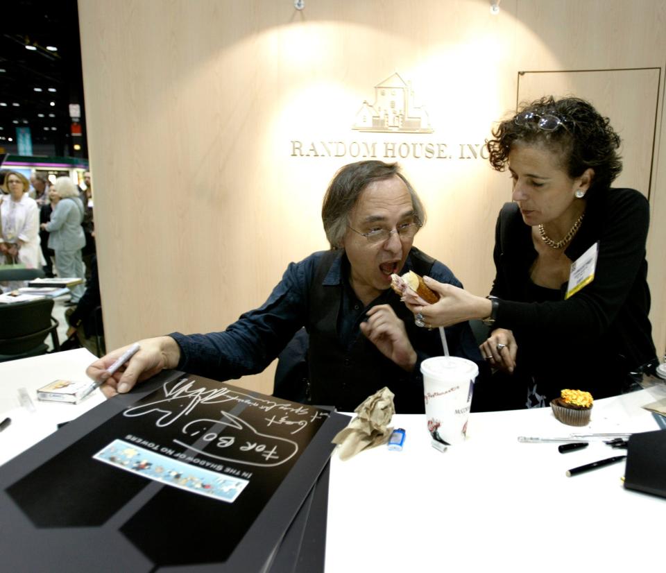 FILE - Artist and author Art Spiegelman gets some help with his lunch from Francoise Mouly, of Random House, Inc., during a signing of Spiegelman's new book "In the Shadow of No Towers" at the Book Expo America convention, Saturday, June 5, 2004, in Chicago.  A Tennessee school district has voted to ban a Pulitzer Prize winning graphic novel about the Holocaust due to "inappropriate language" and an illustration of a nude woman. That's according to minutes from the McMinn County School Board meeting on Jan. 10, 2022.  Board members voted to remove "Maus," a graphic novel by Art Spiegelman. (AP Photo/Brian Kersey, File)