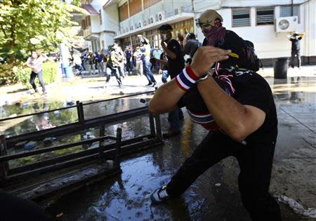 Anti-government protesters take cover as they throw rocks at Thai riot police as they attack Government House in Bangkok December 1, 2013. REUTERS/Dylan Martinez