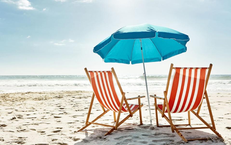 still life shot of two deck chairs under an umbrella on the beach