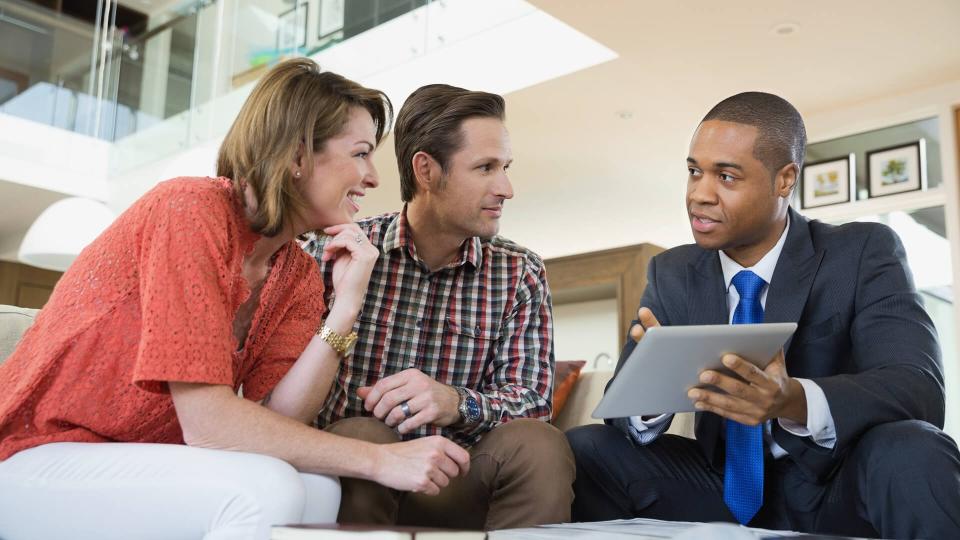 Couple talking to financial advisor in living room.