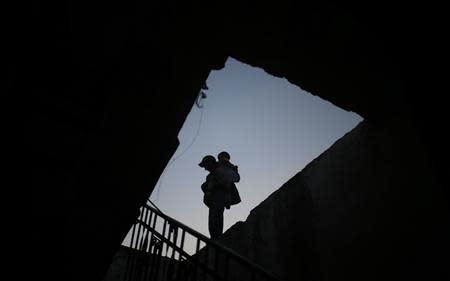 A Palestinian boy carries his sister atop the roof of their family's house in the northern Gaza Strip March 20, 2014. REUTERS/Mohammed Salem