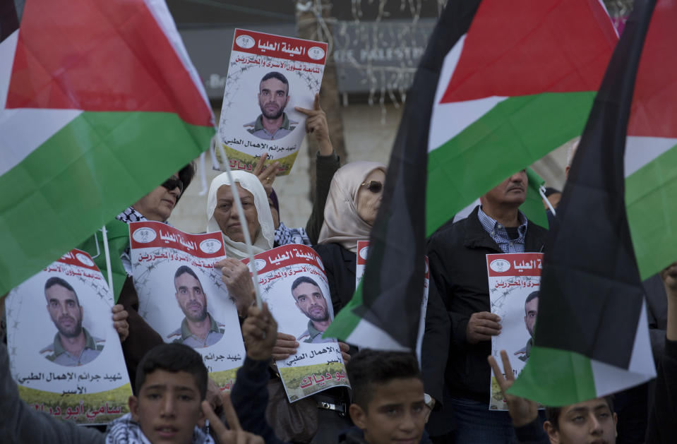 Protesters fly Palestinian flags and carry posters with pictures of Palestinian prisoner in Israeli jail, Sami Abu Diak, who died this morning, during a protest in the West Bank city of Ramallah, Tuesday, Nov. 26. 2019. Diak died Tuesday in Israeli custody after battling cancer, Israel's prisons service said, ahead of demonstrations in the West Bank planned before his death. (AP Photo/Nasser Nasser)