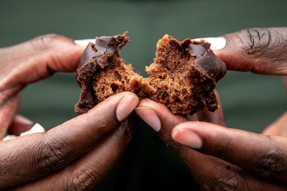 Hands split a Chocolate Old Fashioned doughnut from Randy's Donuts