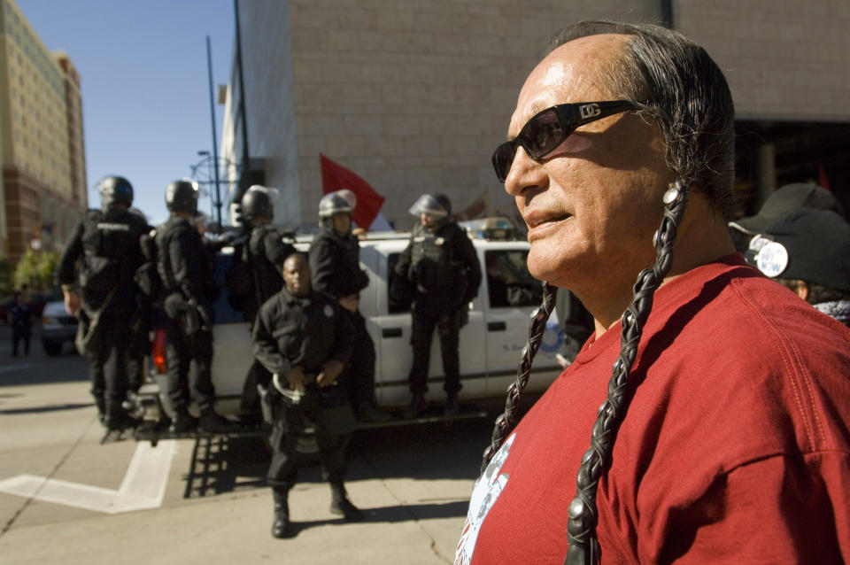 FILE - In this Saturday, Oct. 6, 2007 file photo, American Indian Movement activist Russell Means looks at the start of the Columbus Day Parade in Denver, Colo. Columbus Day became a national holiday in 1968, endorsed by Congress and President Lyndon Johnson as a tribute to immigrants and as a “declaration of willingness to face with confidence the imponderables of unknown tomorrows,” according to a Senate report at the time. But over the past 40 years, as Columbus' image has shifted from the “discoverer of America” to that of a racist and imperialist, some cities and states have either changed the holiday's name or used the day to honor others. (AP Photo/Peter M. Fredin, File)
