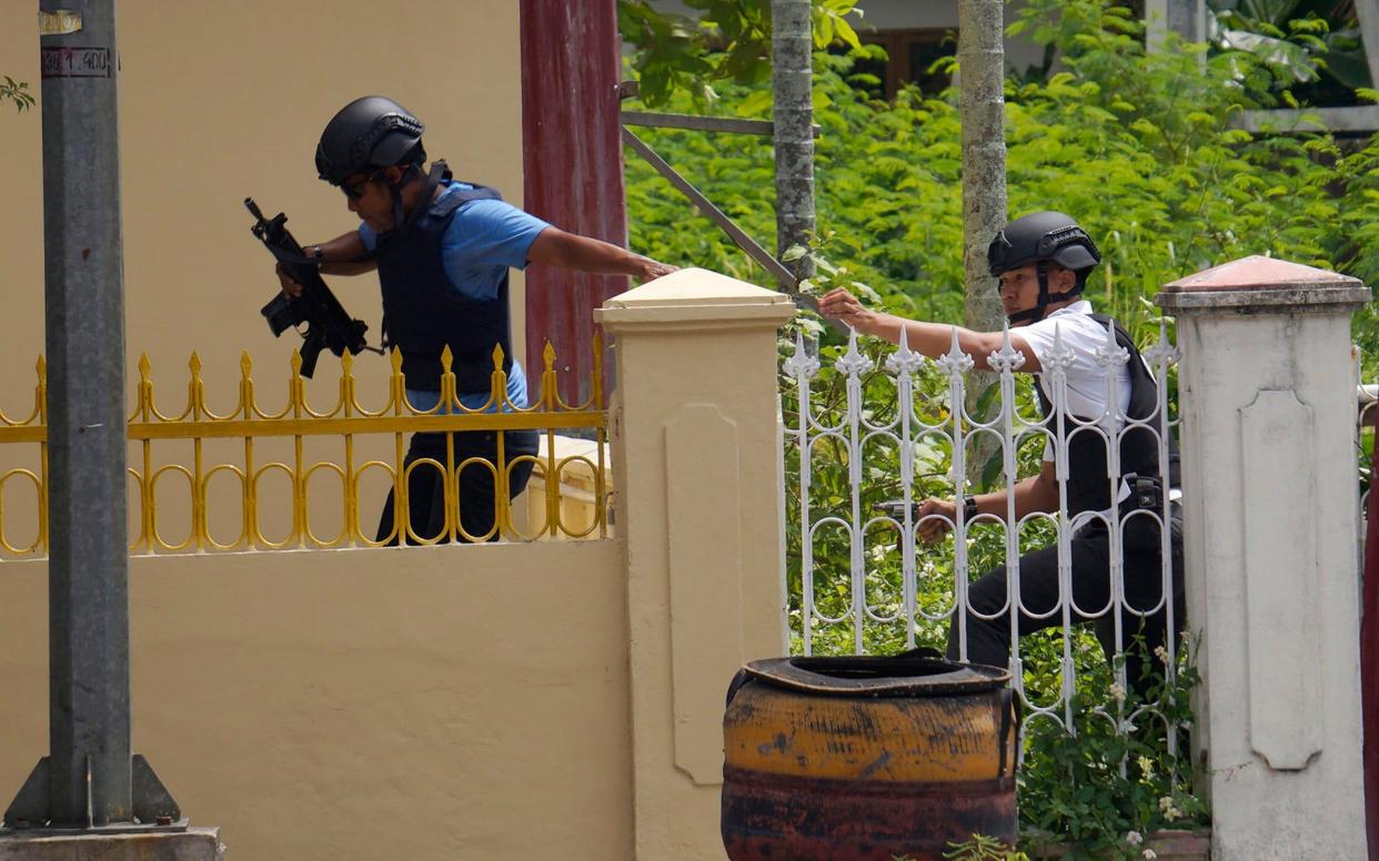 Officers move into position following an attack at the regional police headquarters in Pekanbaru, Riau province, Indonesia - AP