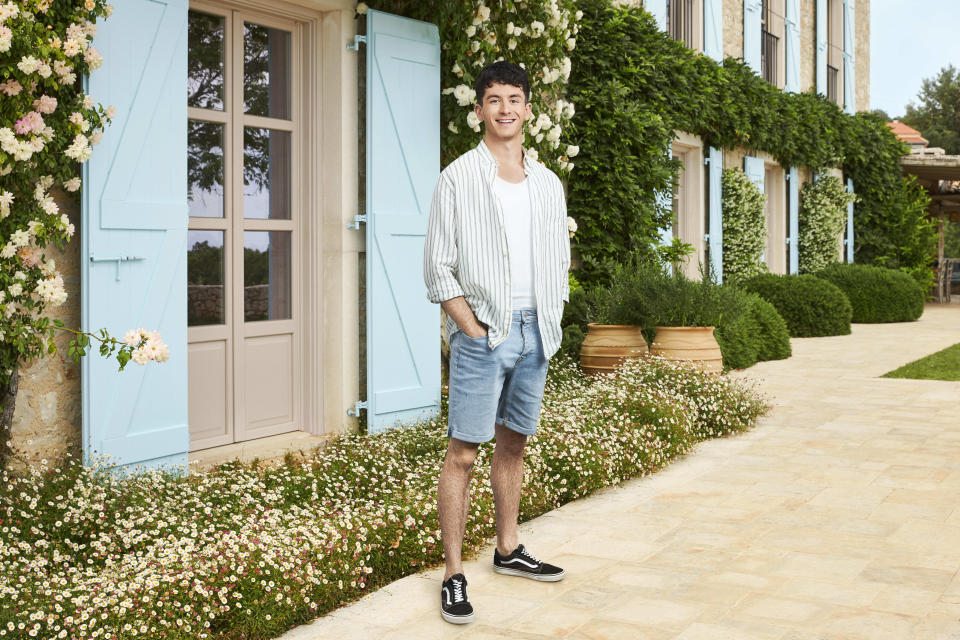 Tobias posing in front of a Greek house with blue shutters.