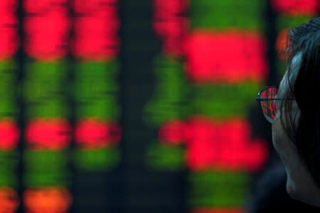 FILE PHOTO: An investor looks at an electronic board showing stock information at a brokerage house in Shanghai, China July 6, 2018. REUTERS/Aly Song/File Photo