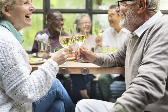 Mature man and woman celebrating toasting glasses of wine