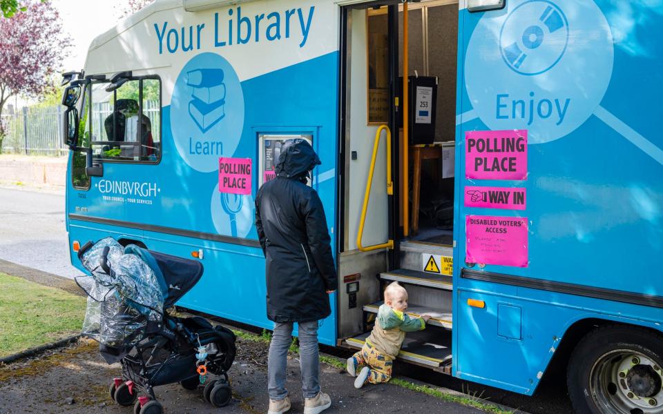 A mother and toddler at a mobile library turned polling station in Drumbrae, Edinburgh