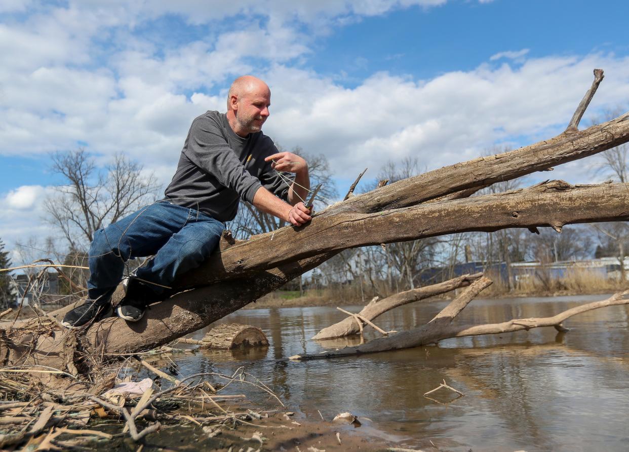 Brian "Lure Hunter" Fisk cuts away a setline from a fallen tree on April 10 along the East River in Green Bay. Fisk, a teacher at East High School, hunts for lost fishing lures and line in and near waterways in northeast Wisconsin. He refurbishes the lures and sells them, with 20% of the proceeds going to funding a fishing tournaments for students each year.