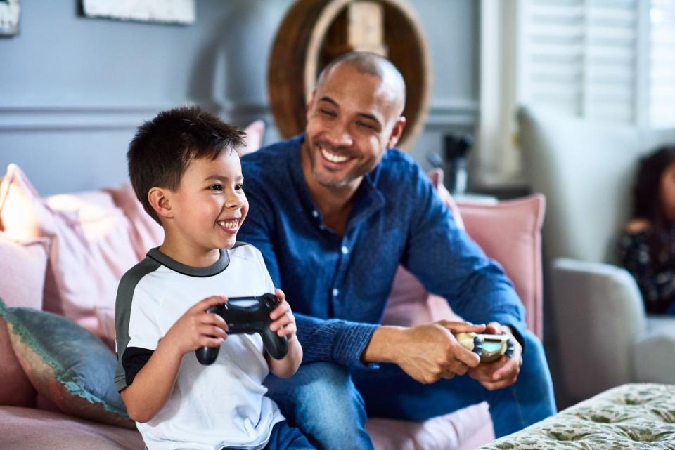 cheerful father playing games console with son