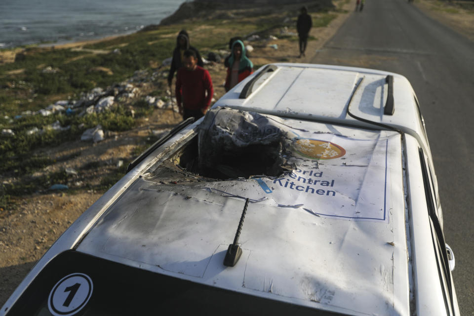 FILE - Palestinians inspect a vehicle with the logo of the World Central Kitchen wrecked by an Israeli airstrike in Deir al Balah, Gaza Strip on April 2, 2024. In Israel's drive to destroy Hamas, the rights groups and workers say Israel seems to have given itself wide leeway to determine what is a target and how many civilian deaths it allows as collateral damage. Israel says it's targeting Hamas and blames the civilian death toll on militants operating among the population. (AP Photo/Ismael Abu Dayyah, File)