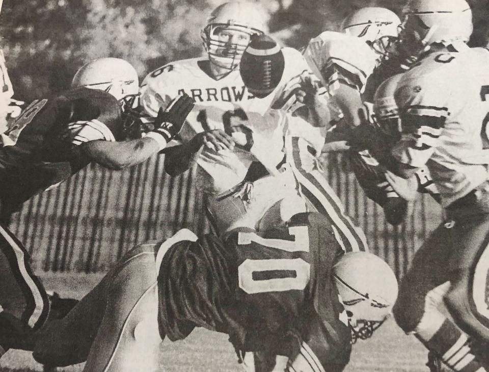 Quaterback Dan Fjeldheim (16) gets hit by Tim Grunditz (left) and Grant Geyerman (70) after pitching the ball to Jeremy Kuno during the Meet the Arrows' scrimmage for Watetown High School's football team in August of 1996.