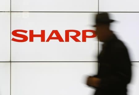 A pedestrian walks past a logo of Sharp Corp at a train station in Tokyo February 3, 2014. REUTERS/Yuya Shino