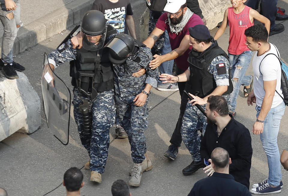A Lebanese riot policeman, left, carries his injured comrade, center, after a clashes erupted between Hezbollah supporters and anti-government protesters during a protest near the government palace, in downtown Beirut, Lebanon, Friday, Oct. 25, 2019. Hundreds of Lebanese protesters set up tents, blocking traffic in main thoroughfares and sleeping in public squares on Friday to enforce a civil disobedience campaign and keep up the pressure on the government to step down. (AP Photo/Hussein Malla)