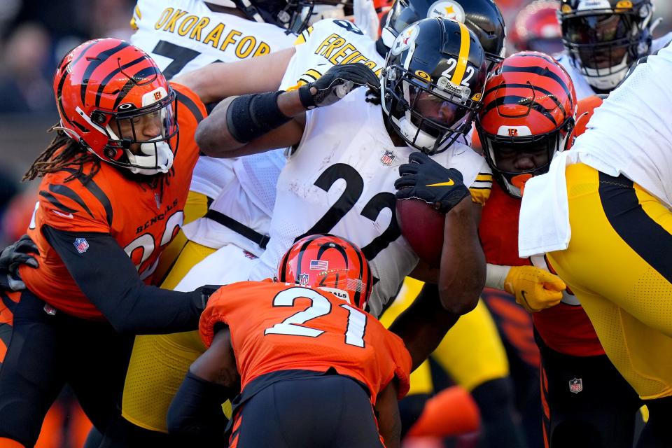 Pittsburgh Steelers running back Najee Harris (22) is tackled by Cincinnati Bengals defensive end Cameron Sample (96) and Cincinnati Bengals cornerback Mike Hilton (21) in the second quarter during a Week 12 NFL football game, Sunday, Nov. 28, 2021, at Paul Brown Stadium in Cincinnati. 