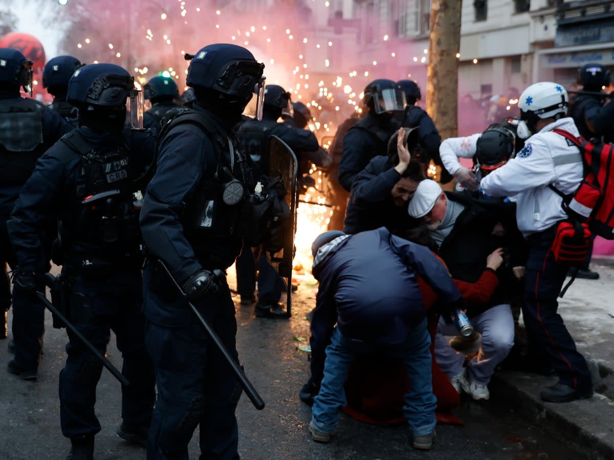 Demonstrators protect themselves near riot police officers in Paris (Lewis Joly/AP)