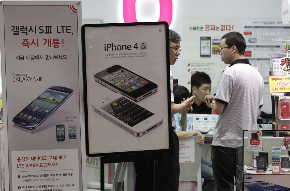 ADDITION FOR CLARIFICATION ON WHERE RULING WAS MADE - Banners advertising Samsung Electronics' Galaxy S III, left, and Apple's iPhone 4S are displayed at a mobile phone shop in Seoul, South Korea, Friday, Aug. 24, 2012. After a year of scorched-earth litigation, a jury in San Jose, Calif., decided Friday, Aug. 24, 2012 that Samsung ripped off the innovative technology used by Apple to create its revolutionary iPhone and iPad. The jury ordered Samsung to pay Apple $1.05 billion. An appeal is expected. (AP Photo/Ahn Young-joon)