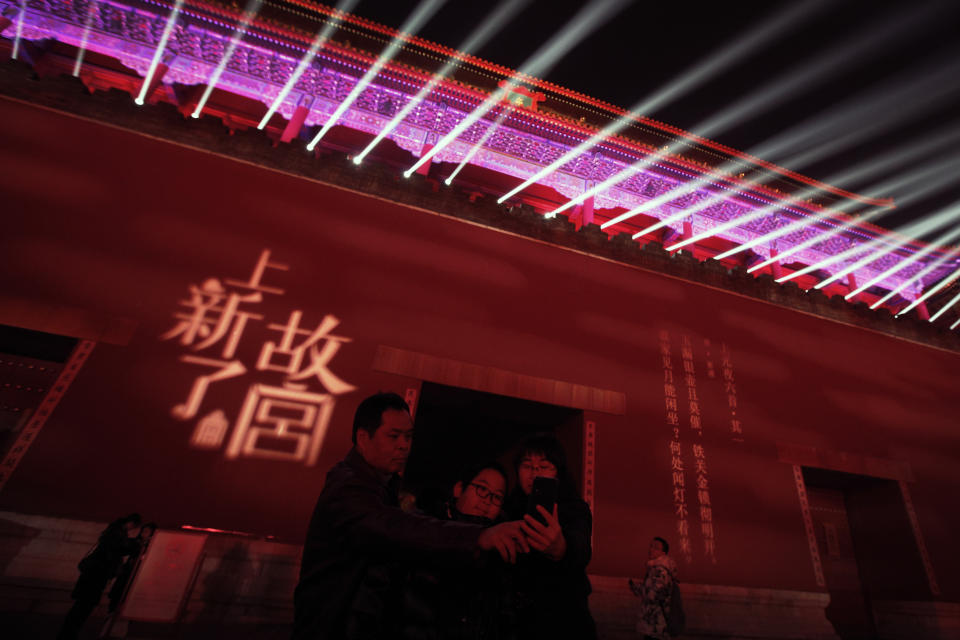 In this Tuesday, Feb. 19, 2019, photo, a family take selfie with the Wumen Gate wall of the Forbidden City illuminated with lights for the Lantern Festival in Beijing. China lit up the Forbidden City on Tuesday night, marking the end of 15 days of lunar new year celebrations. It was not a Lantern Festival the last emperor, who abdicated in 1912, would have recognized. There were lanterns, but those lucky enough to snag tickets saw a laser light show and historic buildings bathed in colorful lights. Others watched from outside the vast walled compound in Beijing, from where Ming and Qing dynasty emperors ruled for five centuries. (AP Photo/Andy Wong)