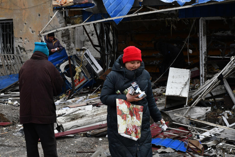 People take cigarettes from a ruined shop in a city market that was damaged following Wednesday's Russian shelling, in Kurakhove, Donetsk region, Ukraine, Thursday, Dec. 8, 2022. (AP Photo/Andriy Andriyenko)