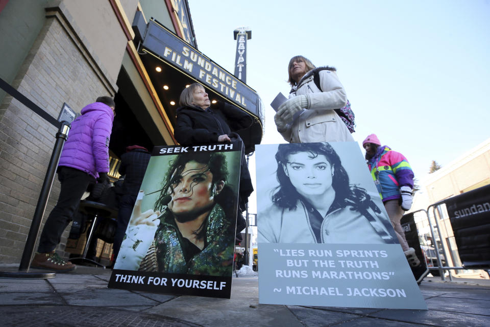 FILE- In this Jan. 25, 2019, file photo Brenda Jenkyns, left, and Catherine Van Tighem who drove from Calgary, Canada stand with signs outside of the premiere of the "Leaving Neverland" Michael Jackson documentary film at the Egyptian Theatre on Main Street during the 2019 Sundance Film Festival in Park City, Utah. Jackson accusers Wade Robson and James Safechuck say that the Sundance Film Festival is first time they've ever felt public support for their allegations the King of Pop molested them. The documentary which premiered at the festival in January, and will air on HBO in two parts on March 3 and 4, chronicles how their lives intersected with Jackson's. (Photo by Danny Moloshok/Invision/AP, File)
