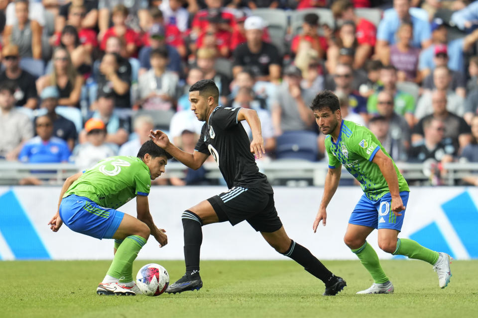 Minnesota United midfielder Emanuel Reynoso, center, controls the ball as Seattle Sounders midfielder Obed Vargas, left, and midfielder Nicolás Lodeiro defend during the second half of an MLS soccer match, Sunday, Aug. 27, 2023, in St. Paul, Minn. (AP Photo/Abbie Parr)