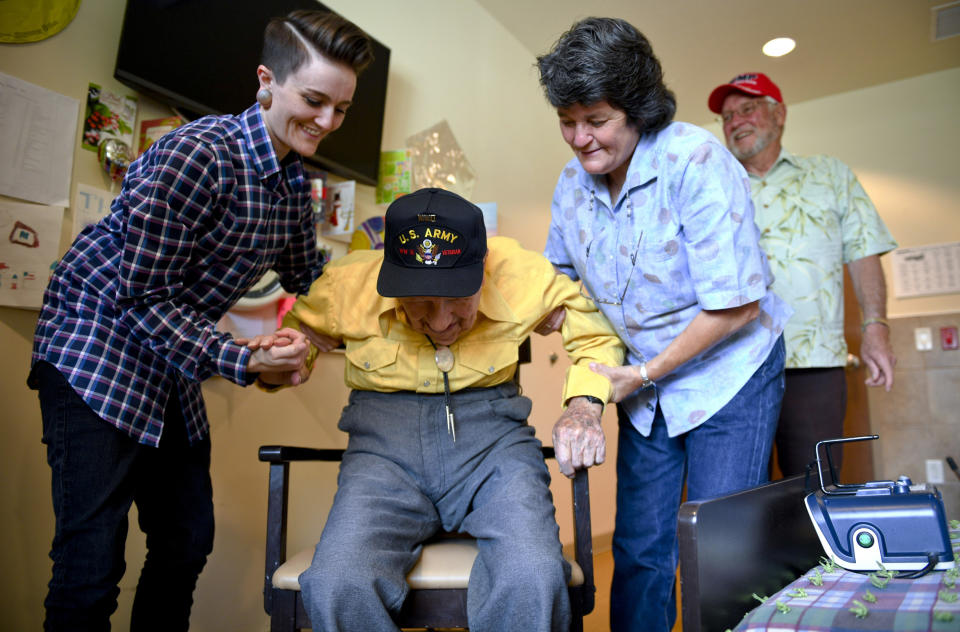 FILE - In this May 6, 2019, file photo, John R. Frey, center, a U.S. Army veteran, is helped out of a chair by his daughter, Janice Carlson, right, and granddaughter, Kara Carlson, as his son-in-law, Gary Carlson, stands by at the Mervyn Sharp Bennion Central Utah Veterans Home in Payson, Utah. Frey, a World War II veteran whose family hoped to help him get 101 cards for his 101st birthday say they have been overwhelmed and grateful as well over 5,000 cards have been sent to Frey. (Isaac Hale/The Daily Herald via AP, File )